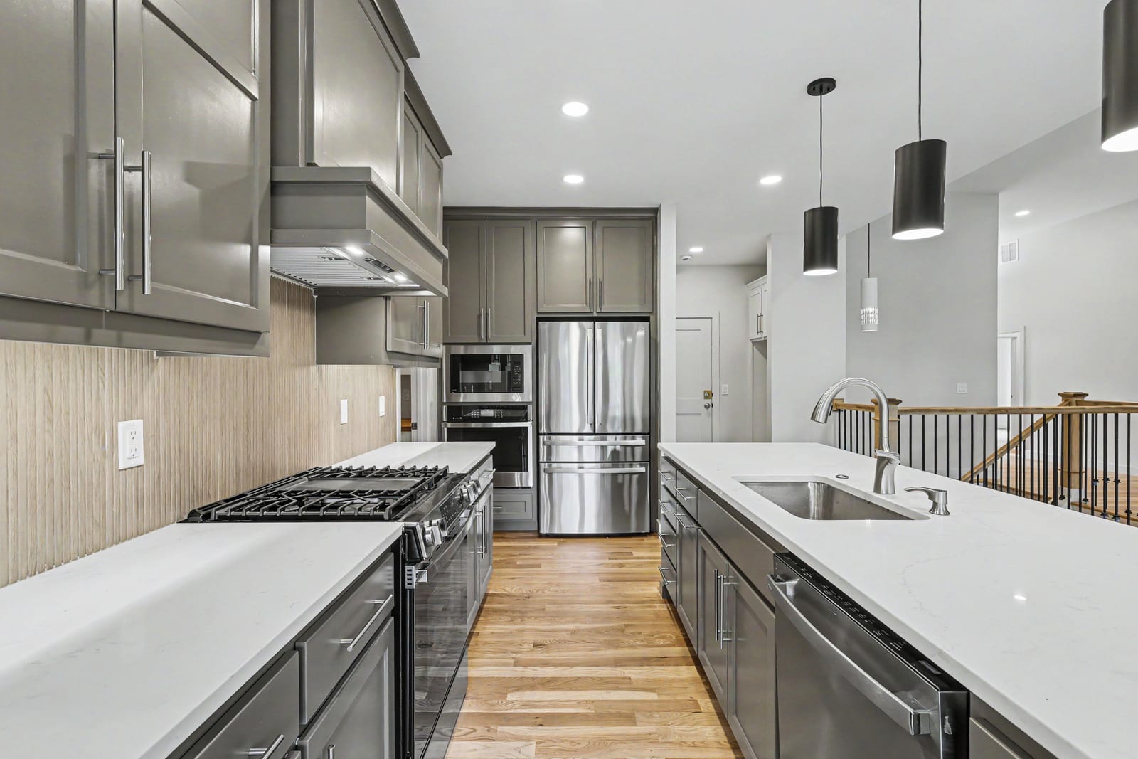 Kitchen with gray cabinetry, hood vent, and stainless appliances